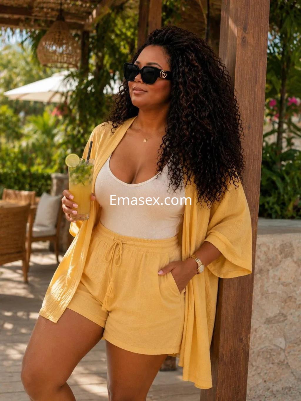 La puta en Oviedo luce un conjunto amarillo con un top ajustado y pantalones cortos, sosteniendo bebidas.