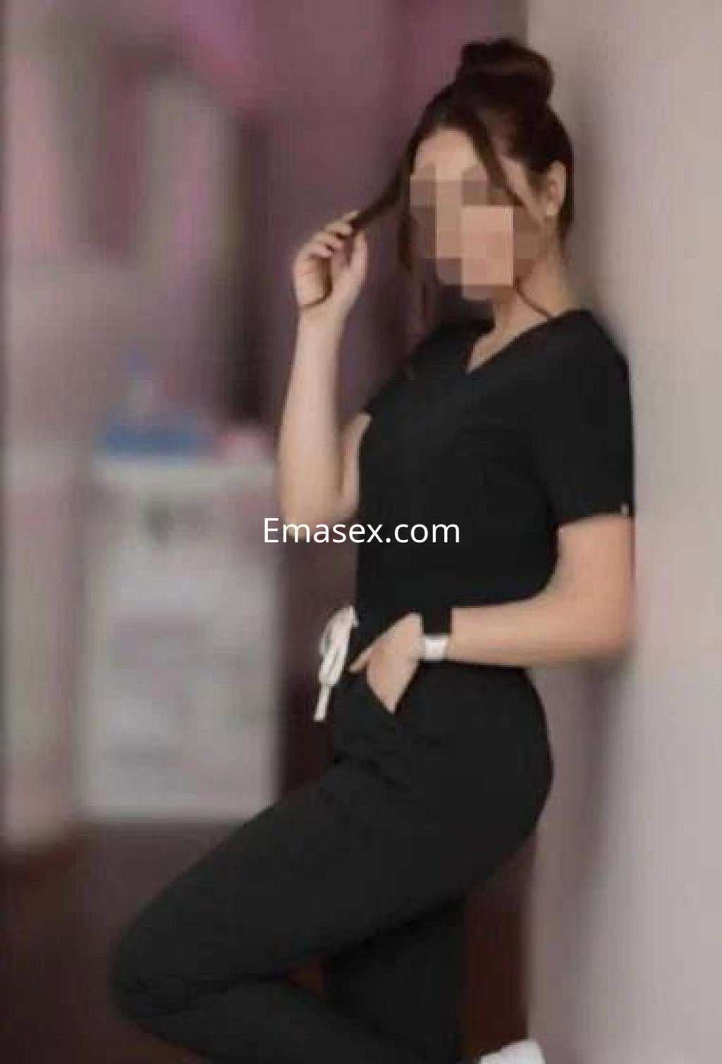 Escort en Murcia con un atuendo negro, posando de lado y tocándose el cabello en un ambiente interior.