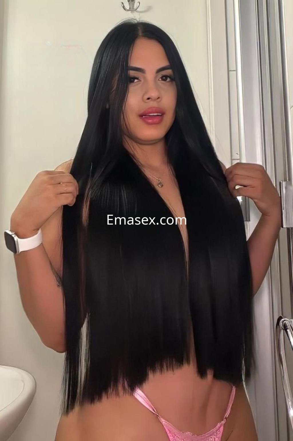 Escort en Tarragona con cabello largo y lacio, vistiendo una lencería rosa, posando en un baño.