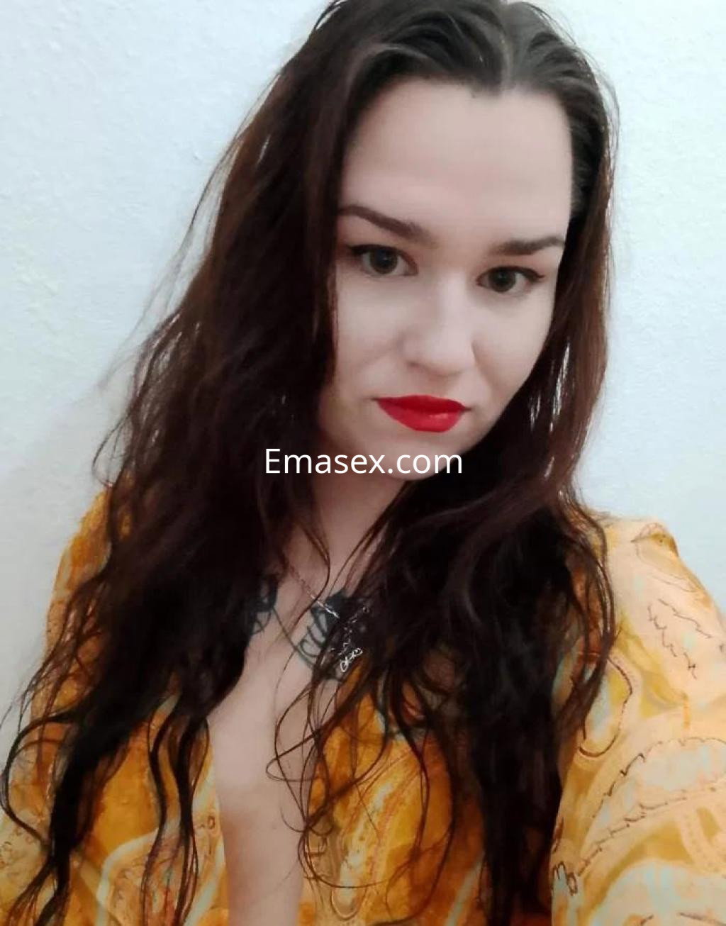 Puta con cabello largo y oscuro, luciendo un vestido amarillo con estampados en un fondo claro en Zaragoza.