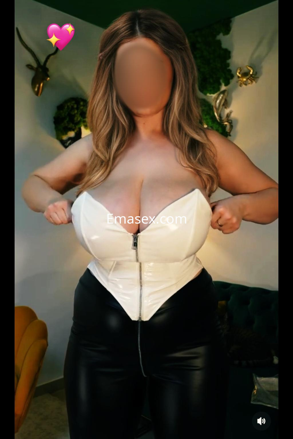 La puta en Irún viste un corset blanco y pantalones negros ajustados, posando con confianza en un entorno moderno.