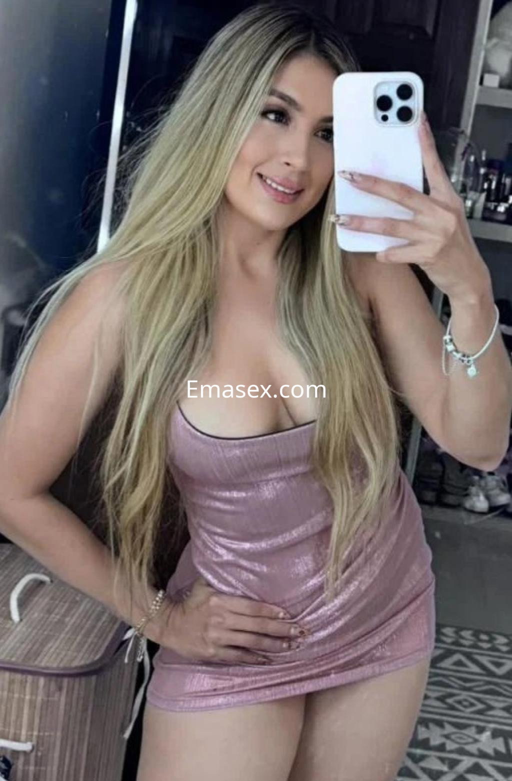Puta en Las Palmas se presenta en una blusa rosa ajustada, mostrando su cabello largo y lacio mientras sonríe.