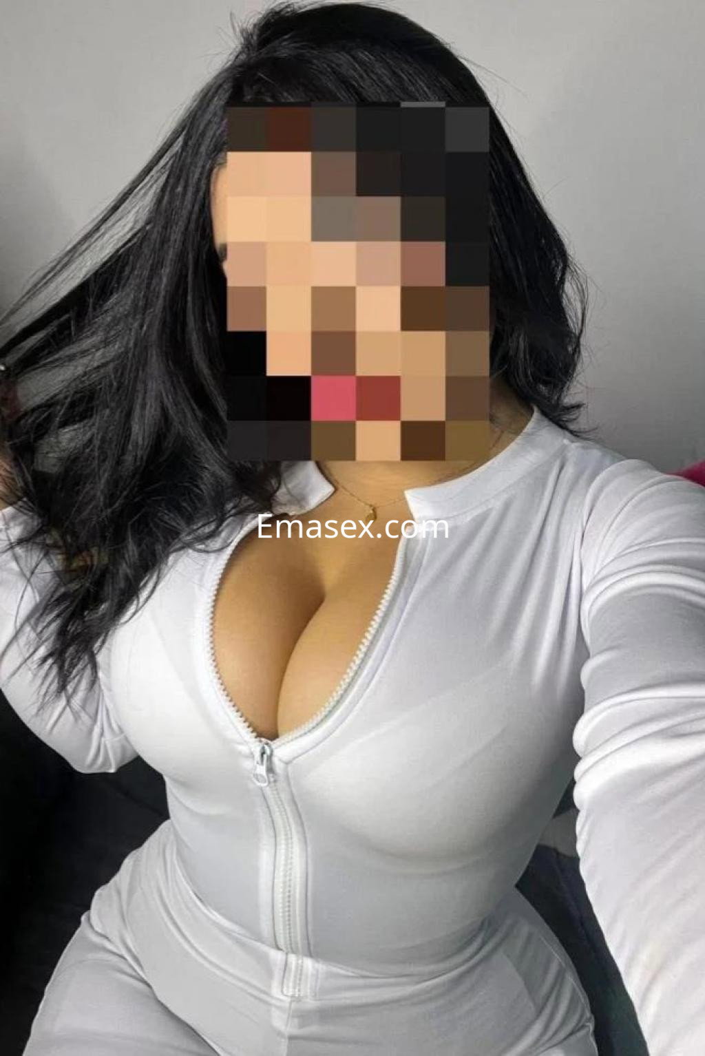 La puta en Coruña luce un ajustado mono blanco que resalta su figura, mientras juega con su cabello.