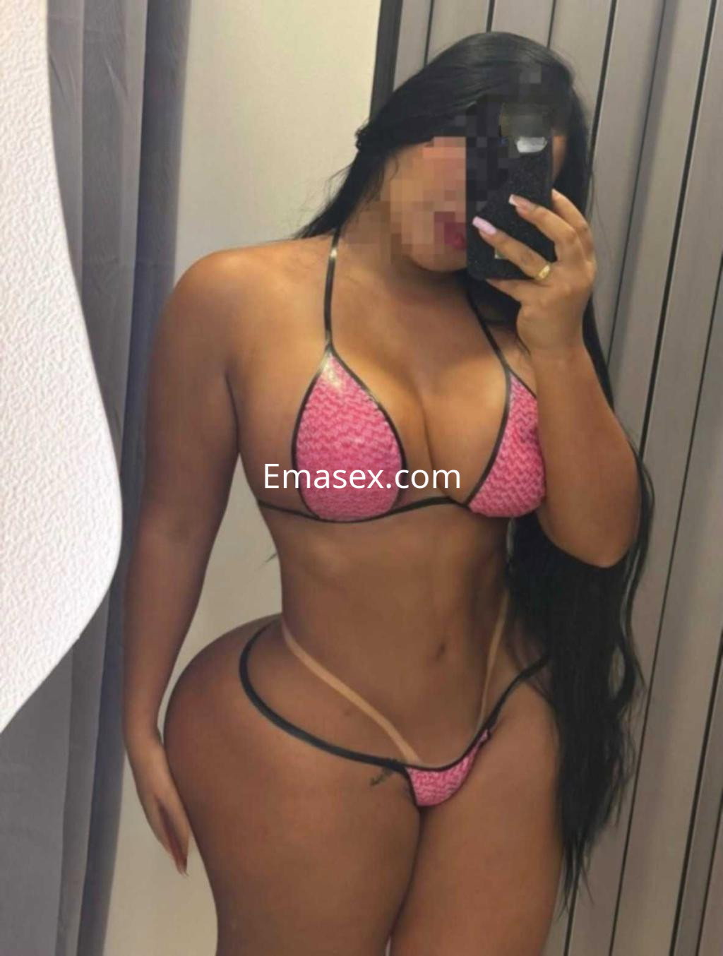 Puta en Cáceres posando con un bikini rosa que resalta su figura, en un entorno de vestidor.