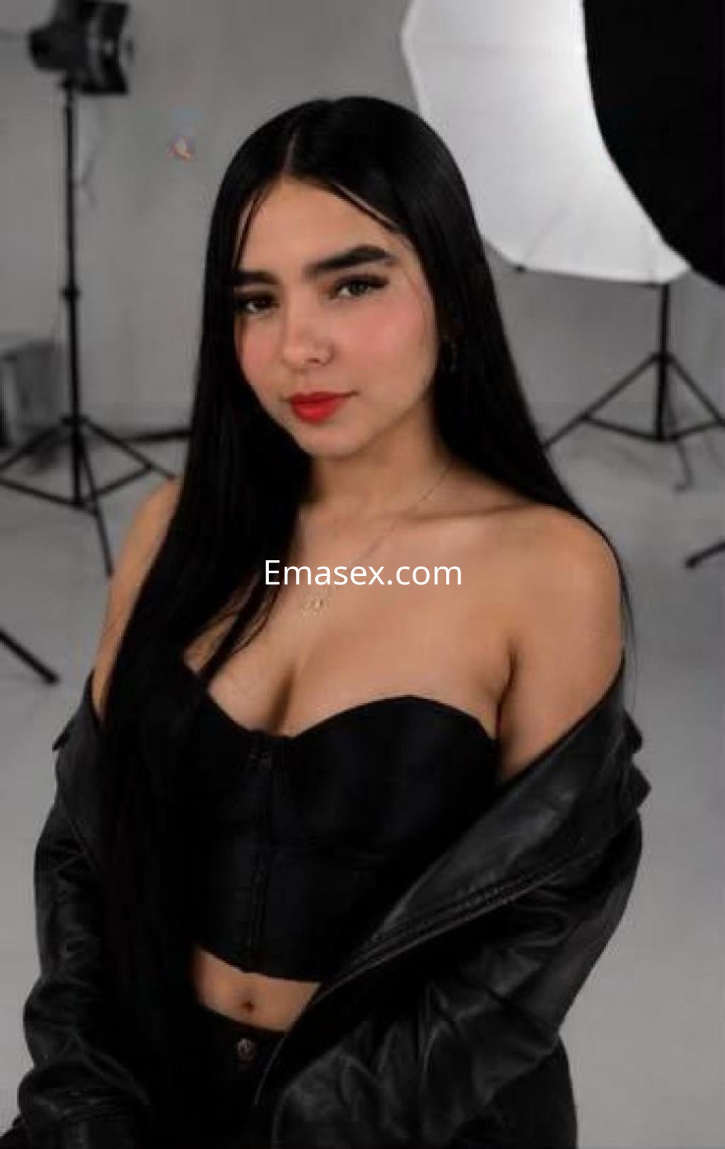 Escort en Almería con cabello largo y lacio, vestida con un top negro sin mangas y chaqueta de cuero.