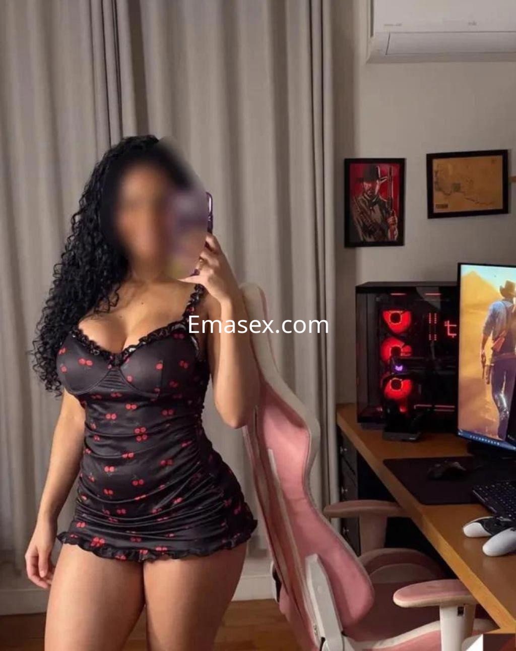 Escort en Las Palmas, luciendo un vestido negro con estampado de cerezas en un entorno moderno y acogedor.