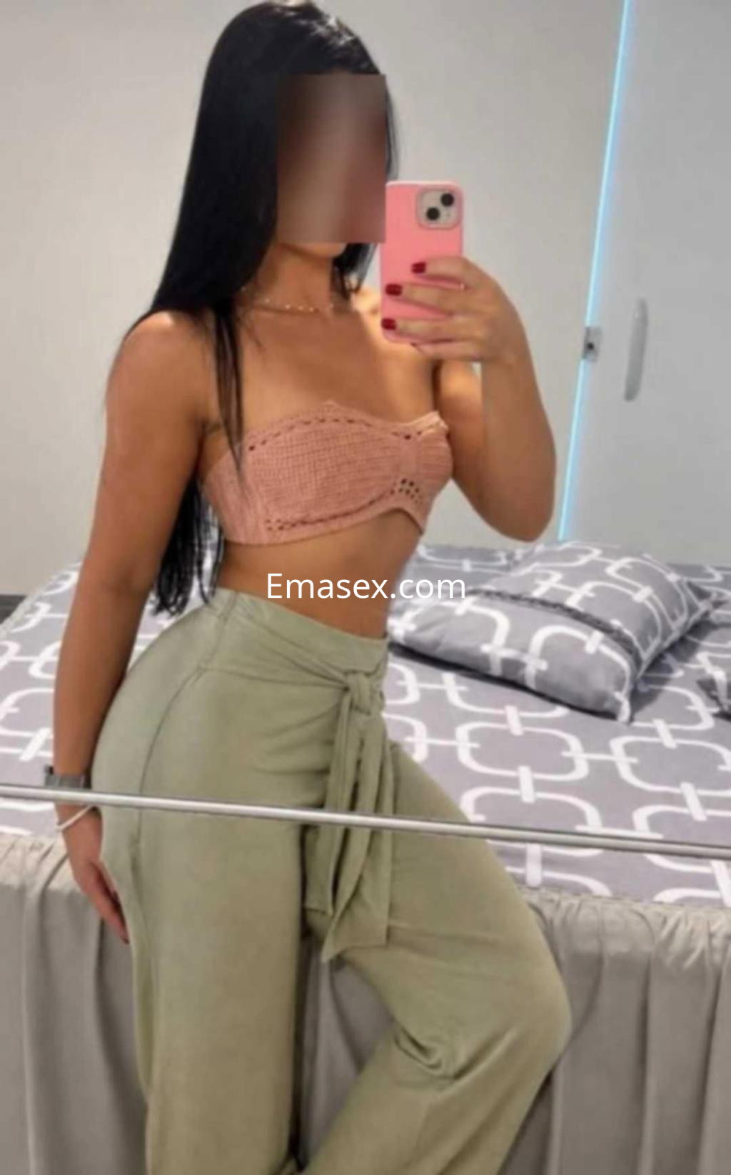 Puta de Badajoz posa en un espejo con un top de crochet rosa y pantalones holgados verdes, mostrando su figura.