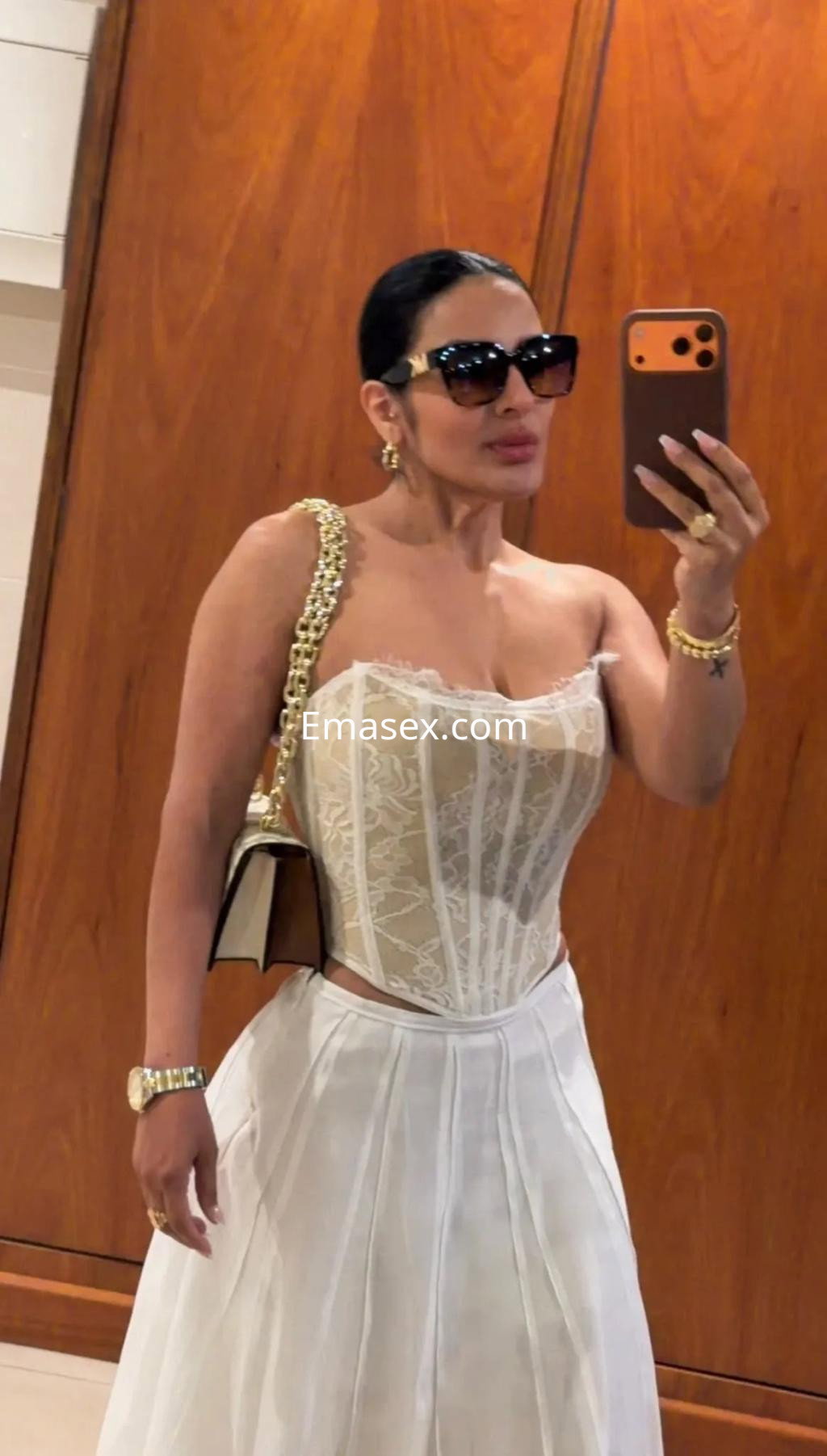 La puta se muestra en un elegante corsé beige con encaje y una falda blanca, posando con gafas de sol en Alicante.