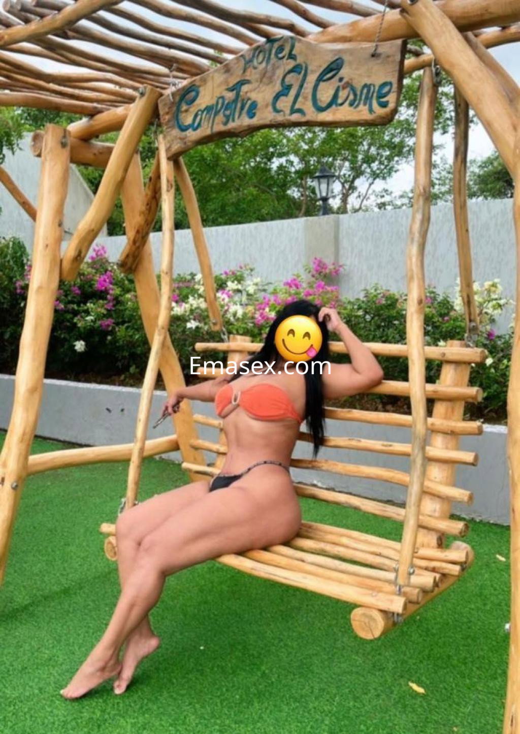 Puta posando en un columpio de madera con un bikini naranja en un entorno natural de Toledo.