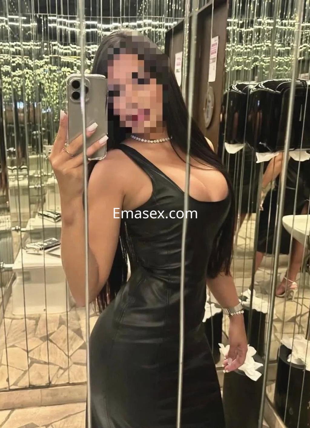 Puta en Valladolid, reflejada en un espejo, vistiendo un vestido negro ajustado y con cabello largo y lacio.