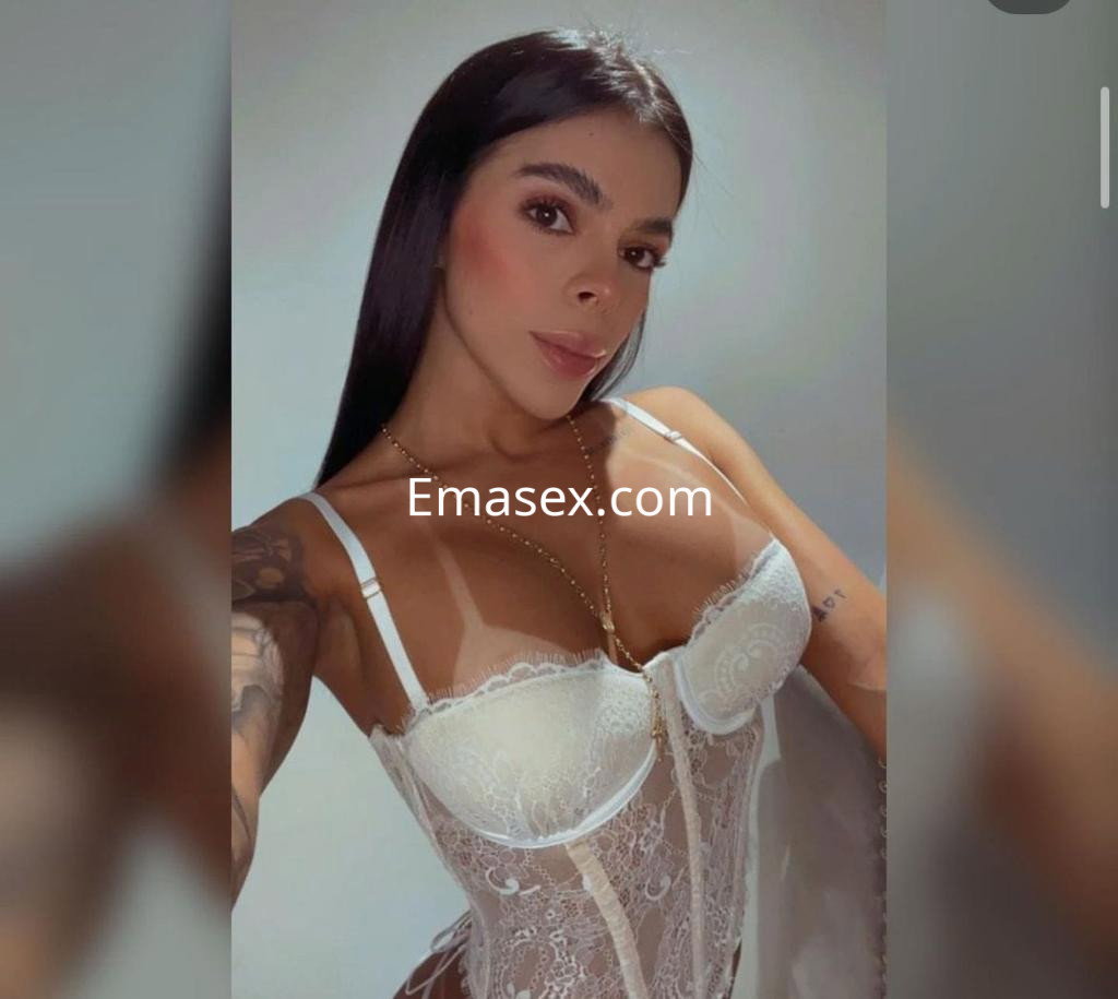 Puta trans en Pamplona luce un conjunto de lencería blanca, con cabello largo y lacio, posando frente a la cámara.