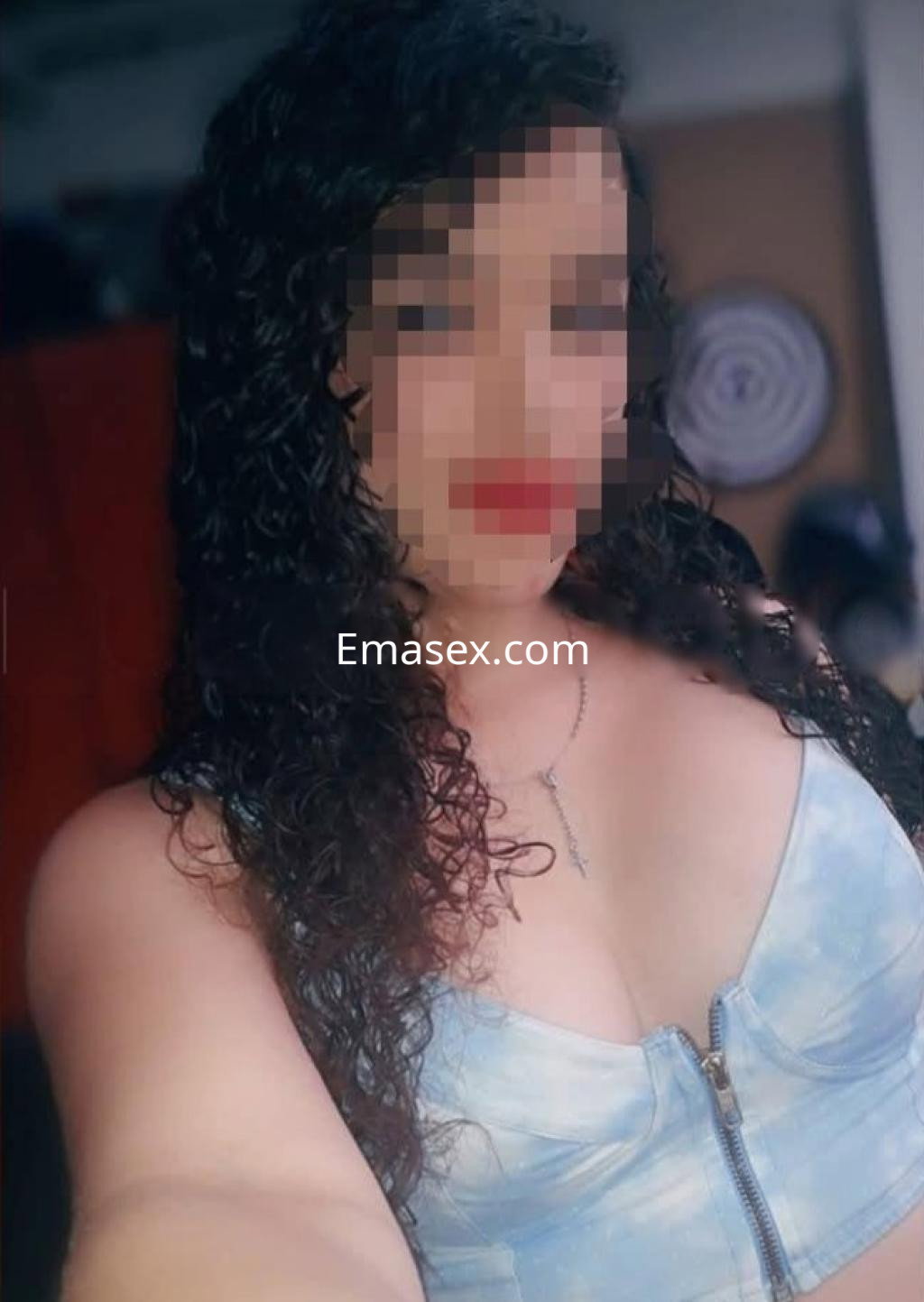 Escort en Barcelona con cabello rizado y oscuro, vistiendo un top de mezclilla que resalta su figura.