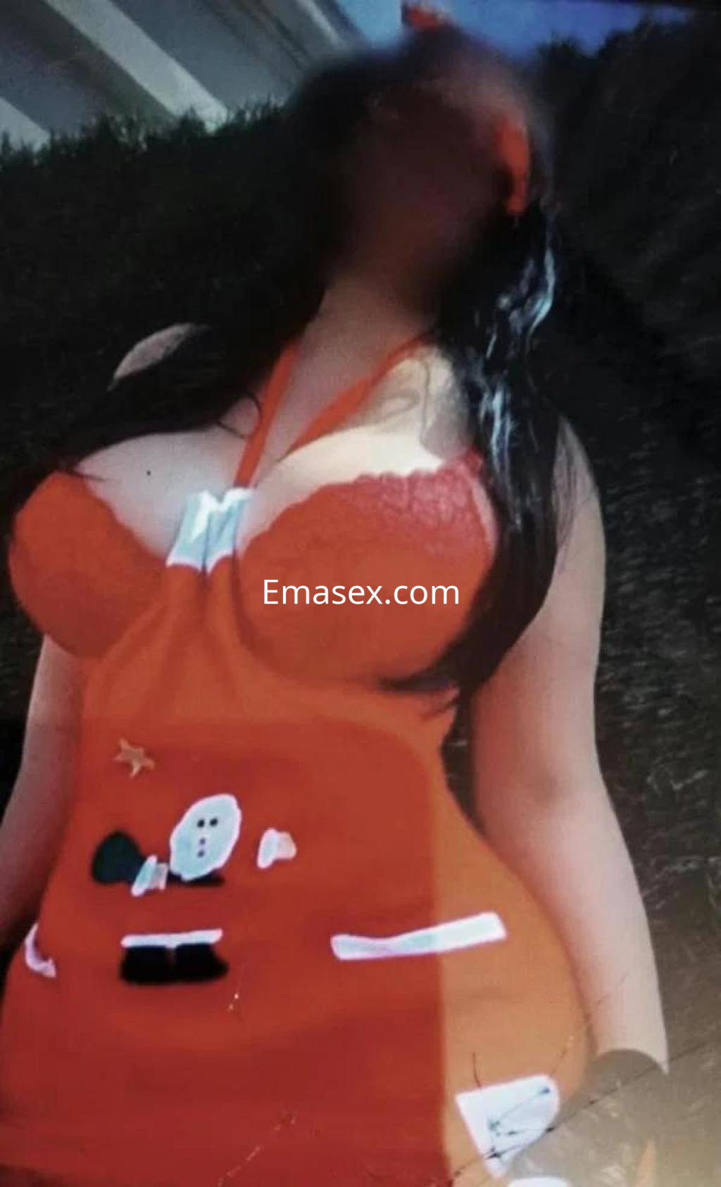 Puta en Toledo viste un disfraz rojo con detalles navideños, mostrando su figura y cabello largo y oscuro.