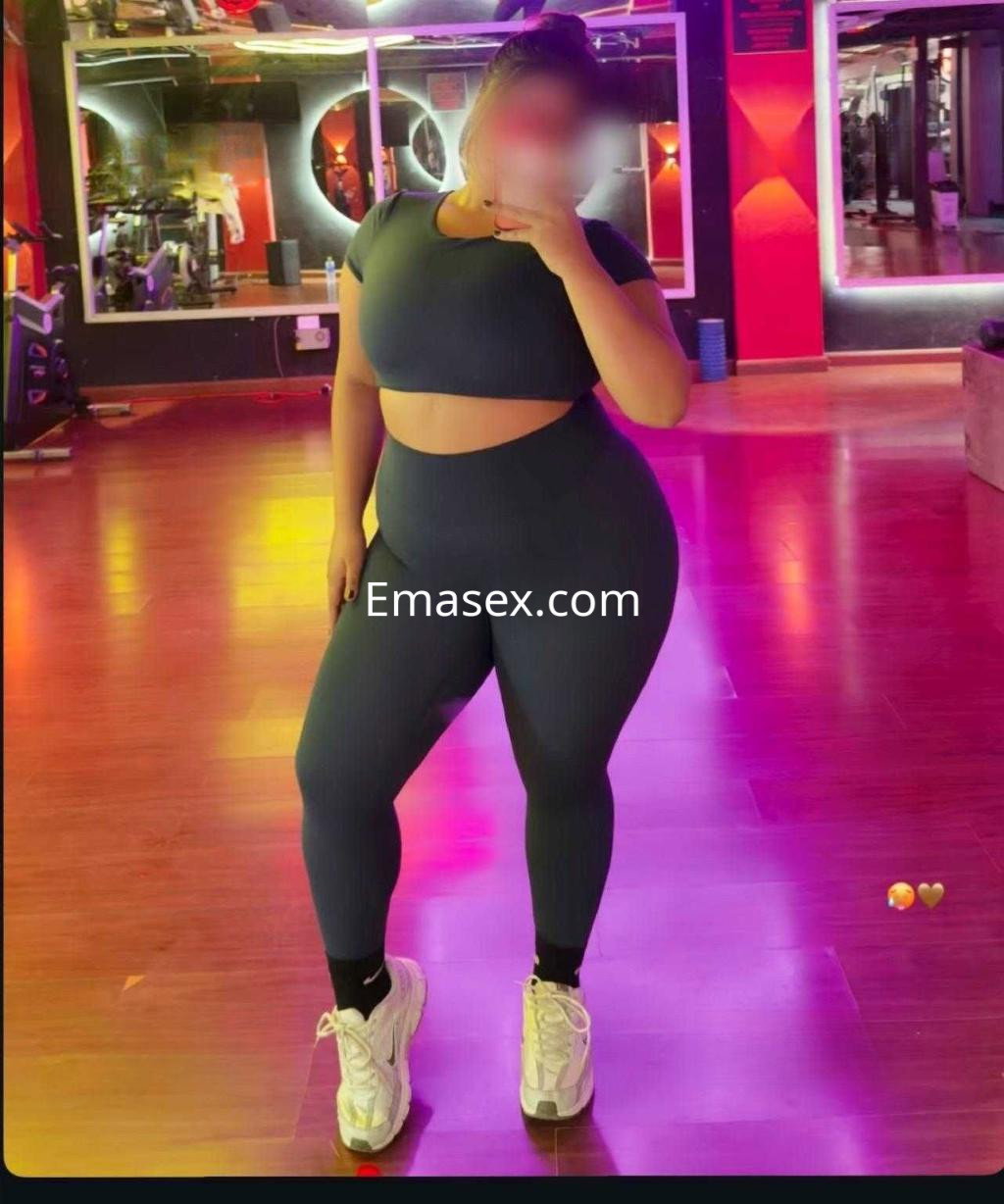 Puta en Badajoz vestida con un conjunto deportivo ajustado, posando en un gimnasio con luces de colores.