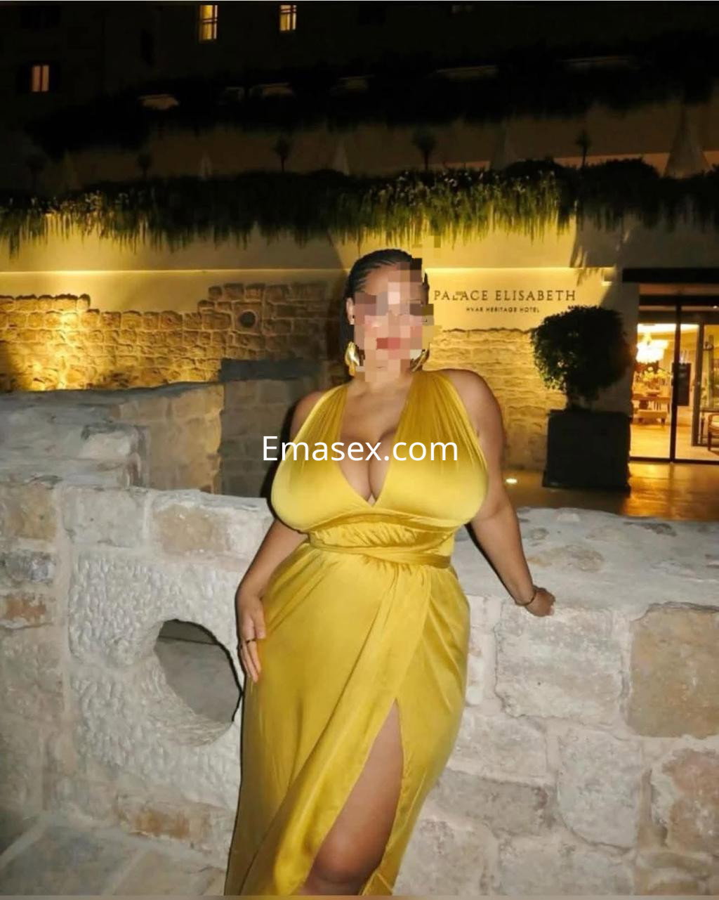 Escort en Irún posando con un vestido amarillo largo que destaca su figura, en un entorno elegante al aire libre.