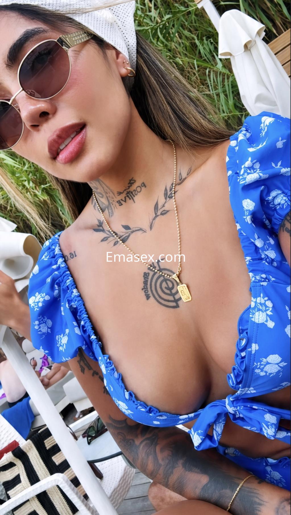 La puta en Vigo se toma un selfie con un bikini azul con flores, luciendo su cabello largo y varios tatuajes.