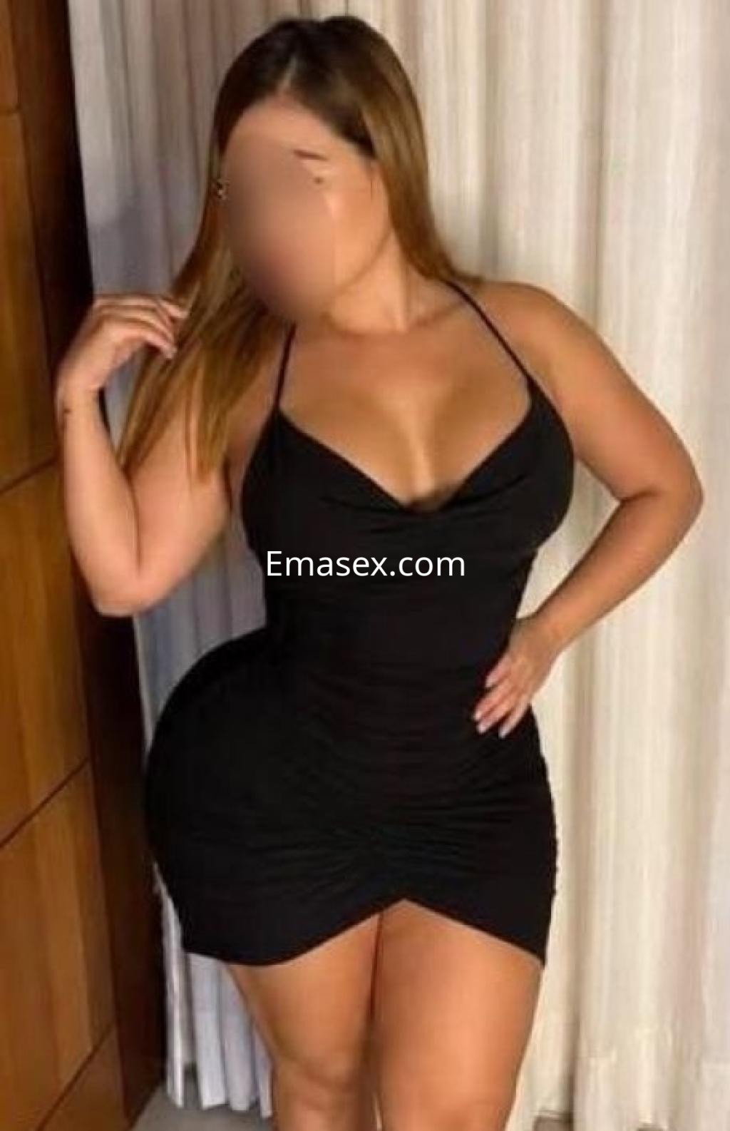 Escort en Córdoba, posando con un vestido negro ajustado que destaca sus curvas, con cabello largo y lacio.