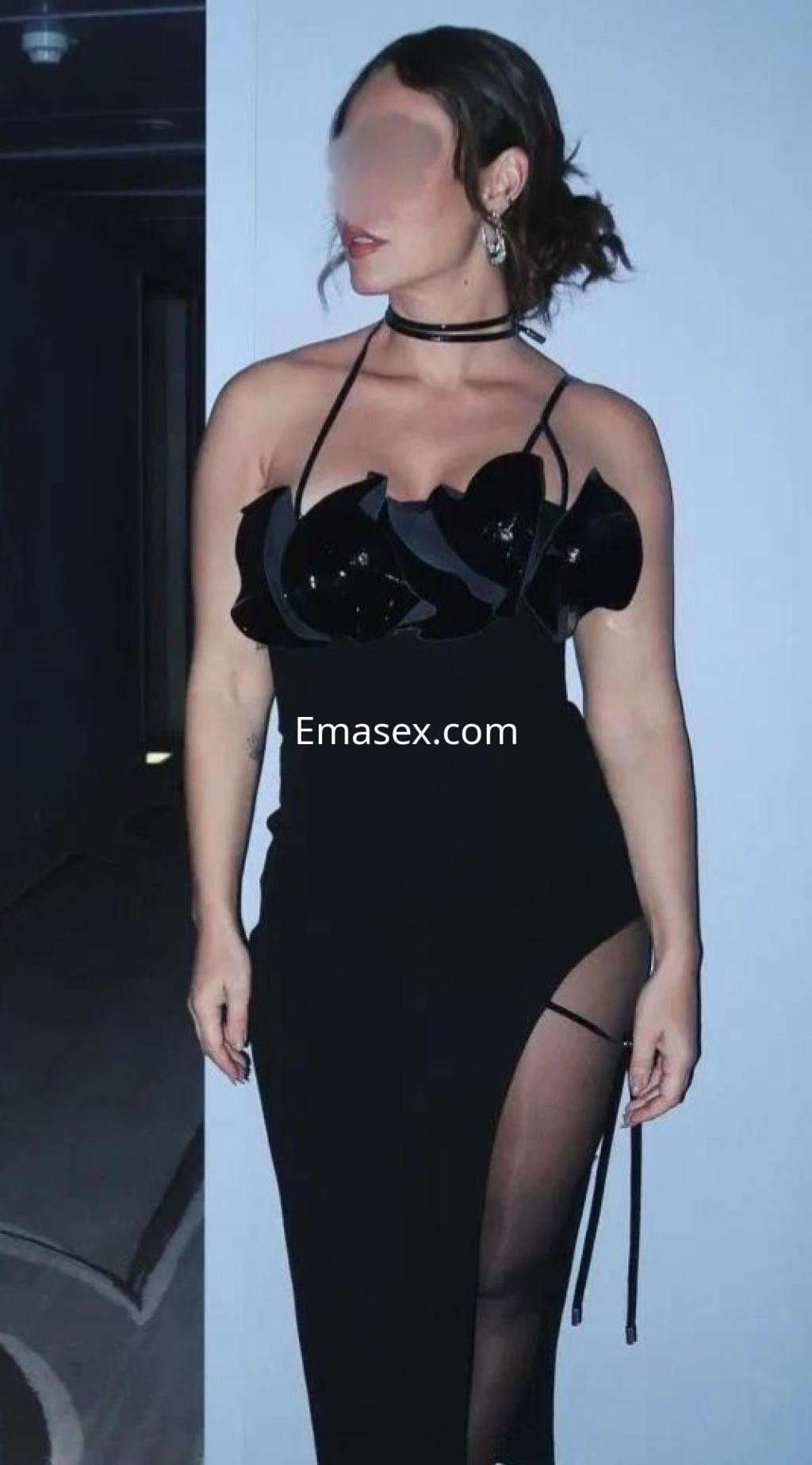 Escort en Badajoz luciendo un vestido negro con detalles brillantes y una abertura lateral, en un entorno elegante.