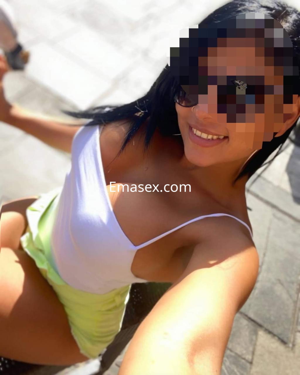 Escort en Logroño luciendo una blusa blanca y pantalones cortos amarillos, con gafas de sol y una sonrisa.