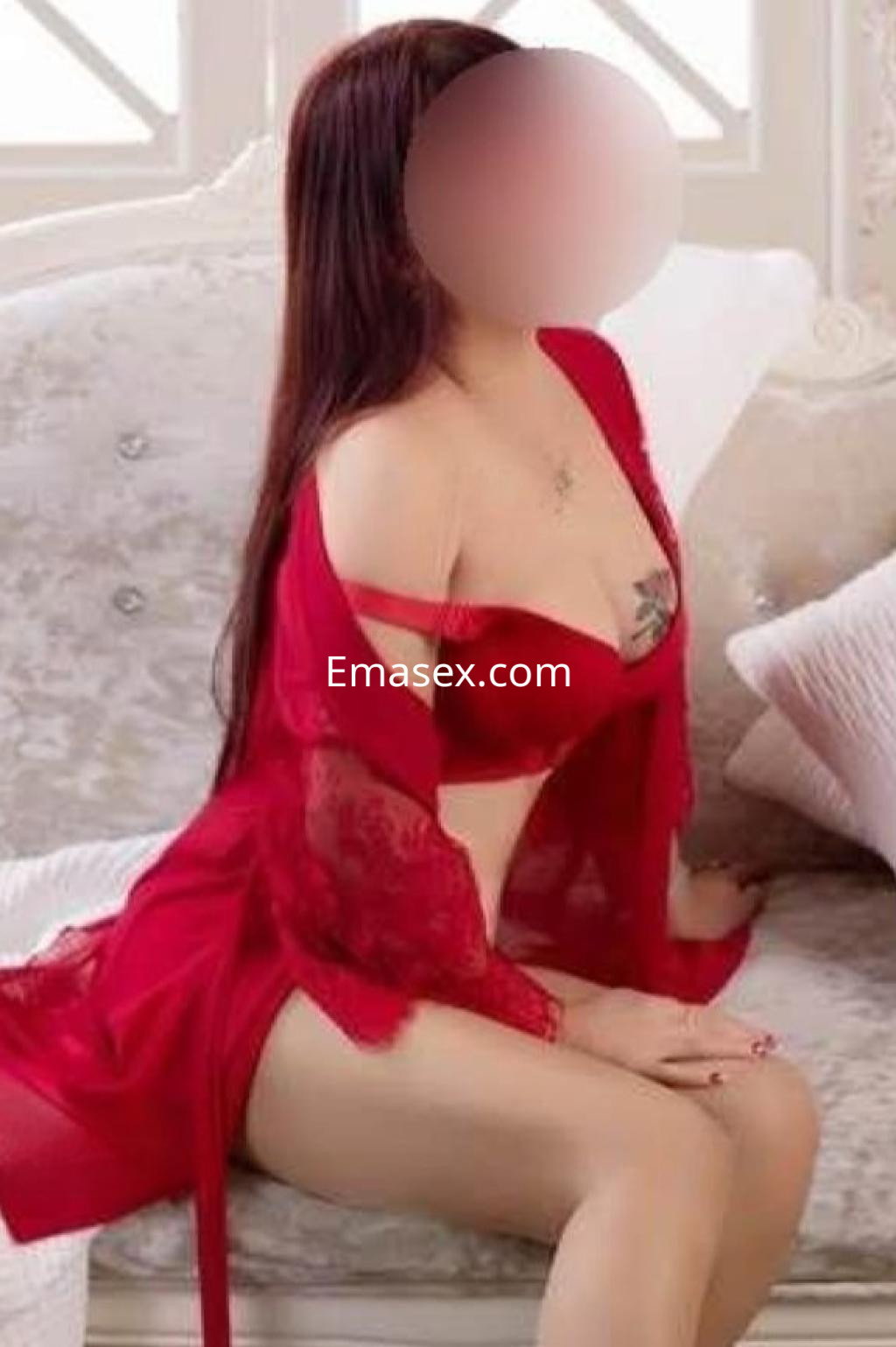 Puta en Córdoba sentada en un sofá, viste lencería roja con encaje y muestra su cabello largo y lacio.