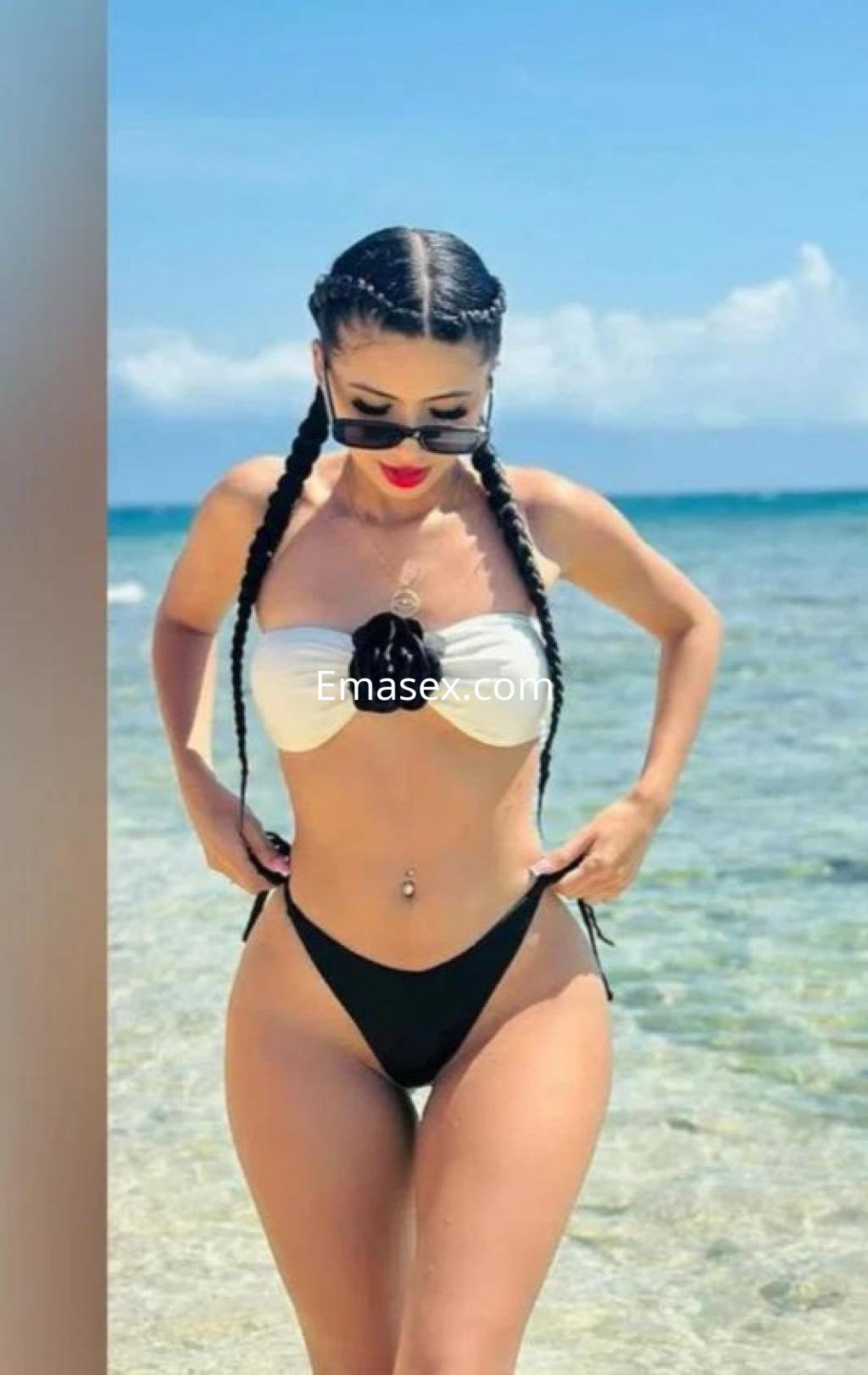 Puta en Las Palmas, luciendo un bikini blanco y negro con trenzas, posando en el agua clara y bronceada.