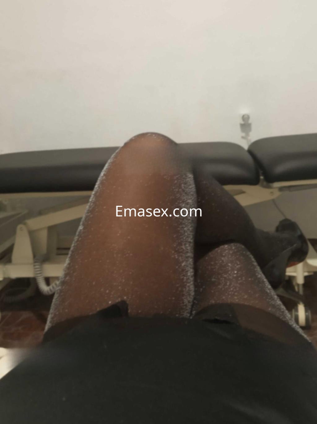 Puta en Granada lleva un vestido negro ajustado y medias brillantes, posando en un entorno interior.