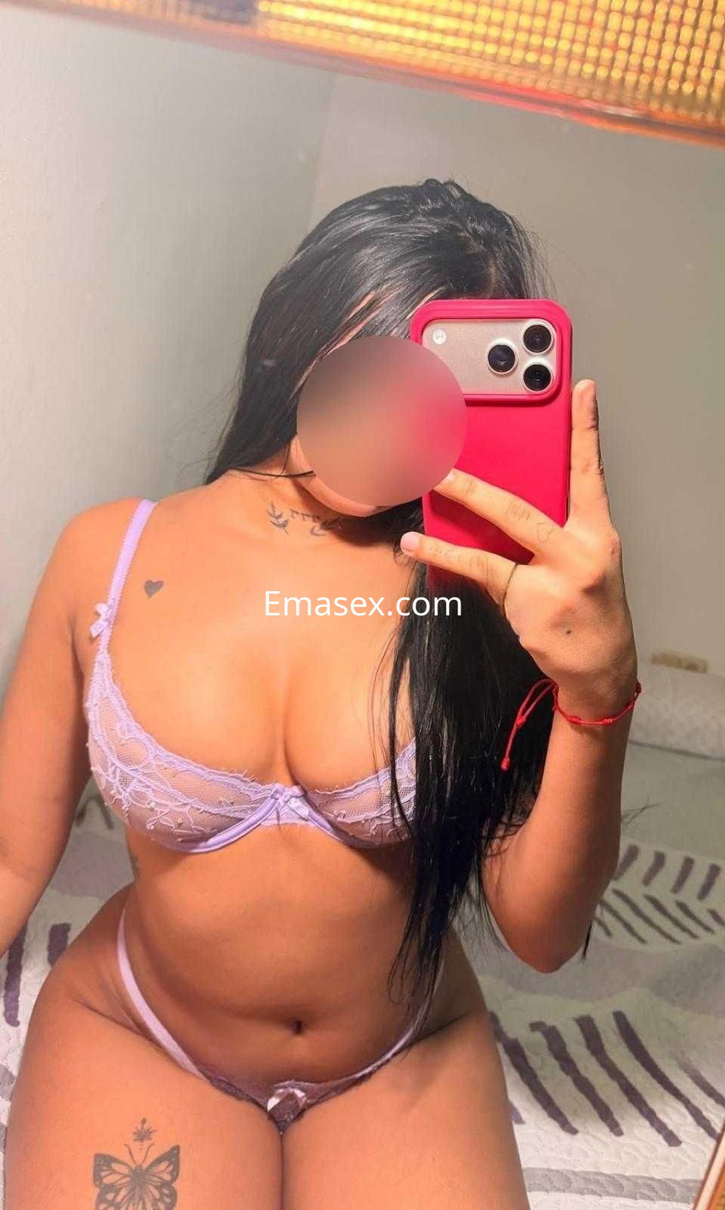 Escort en Granada con lencería lila transparente, tomando una selfie en un entorno acogedor y relajado.