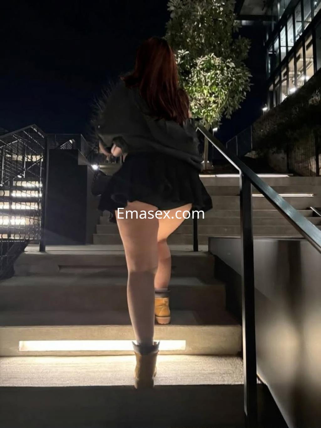 La escort en Donosti sube unas escaleras, vistiendo una falda corta y un abrigo, con cabello largo y suelto.