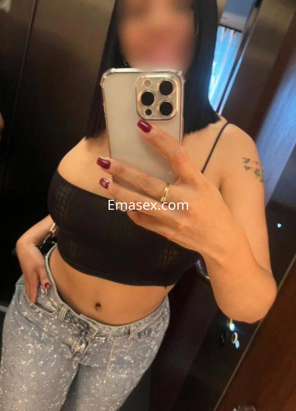 La escort en Las Palmas lleva un top negro y jeans claros, posando frente a un espejo con una sonrisa.