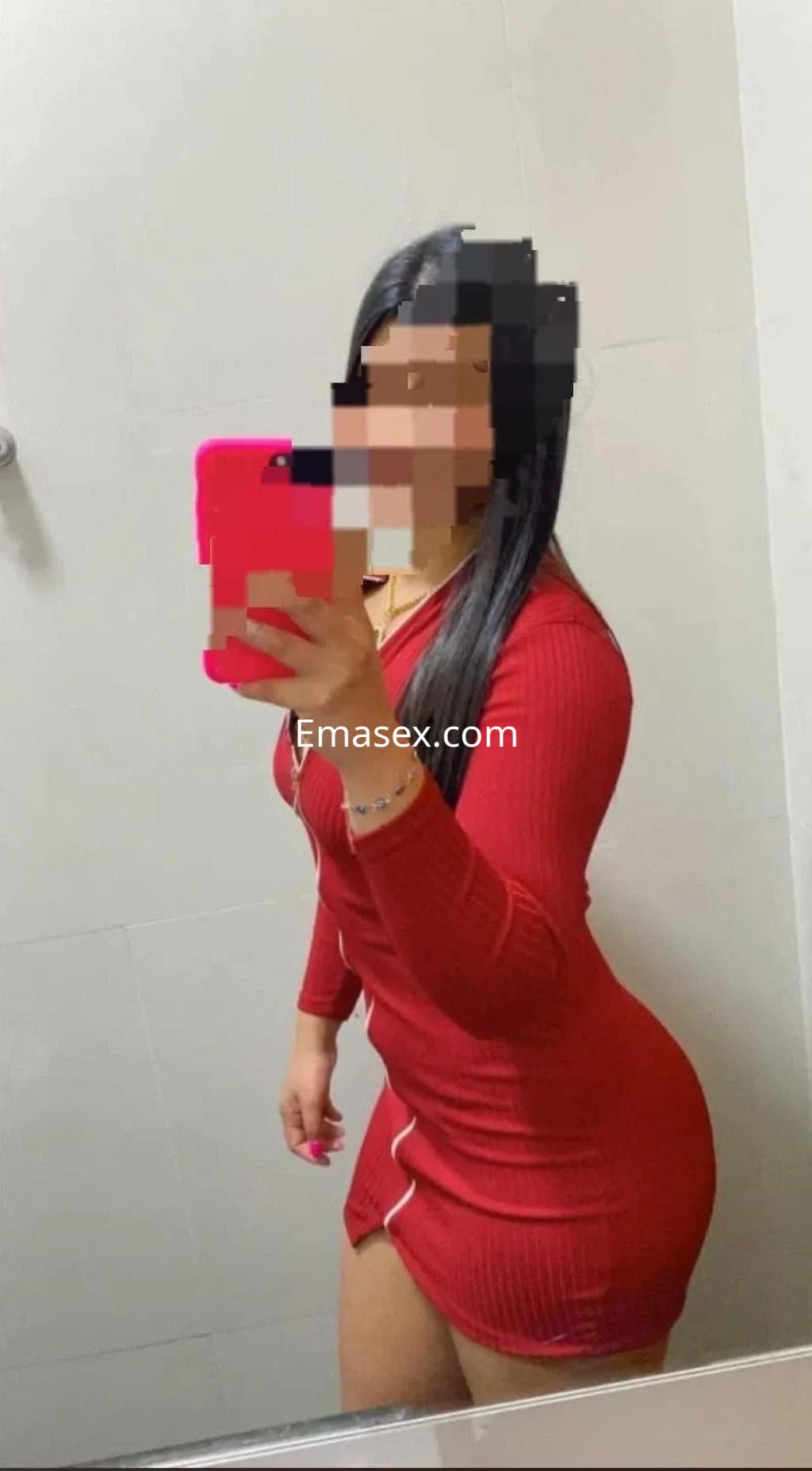 Puta en Albacete con vestido rojo ajustado que resalta su figura, posando frente a un espejo.