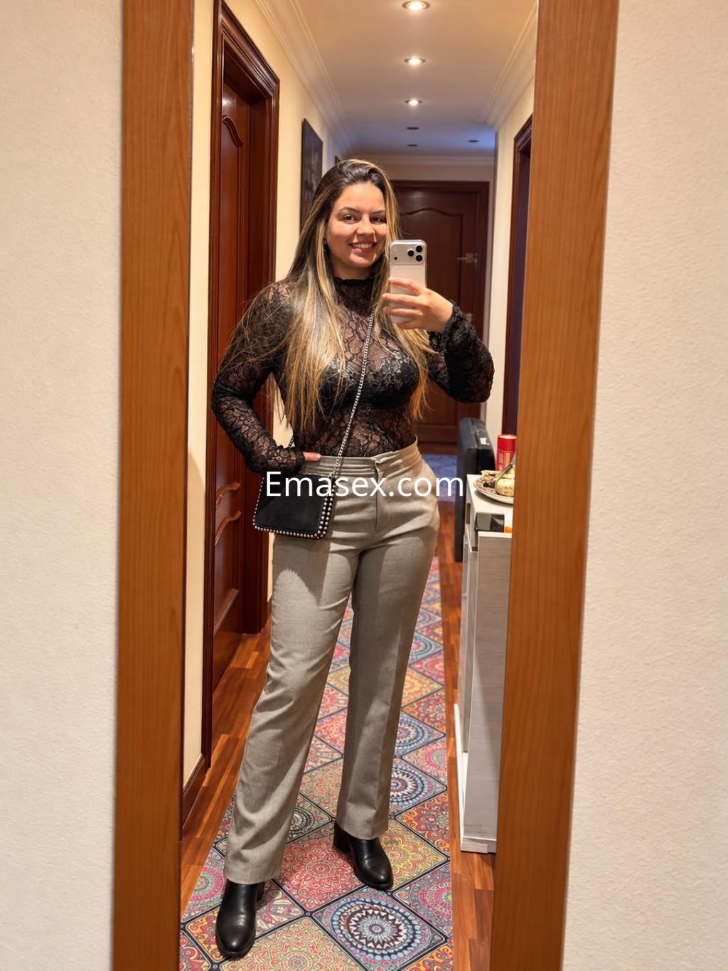 Puta en Santander vistiendo un top negro de encaje con pantalones grises, posando frente a un espejo.