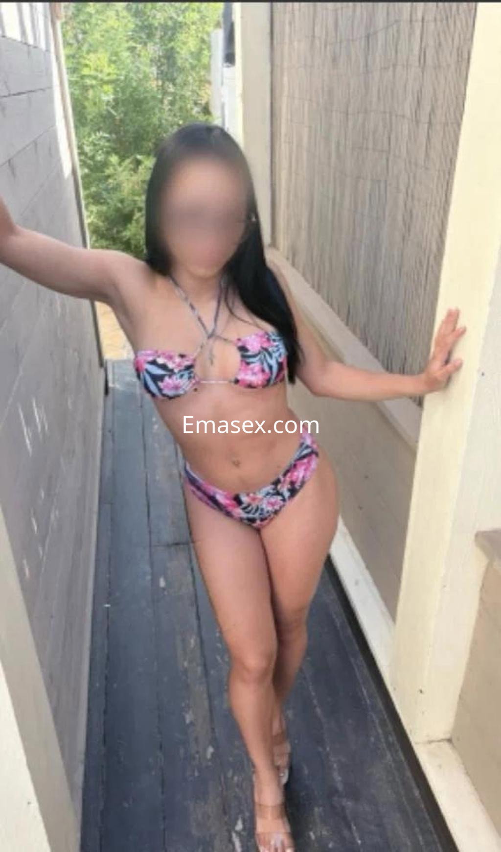 Puta en Las Palmas, luciendo un bikini de flores y posando con una mano en la pared, mostrando su figura.