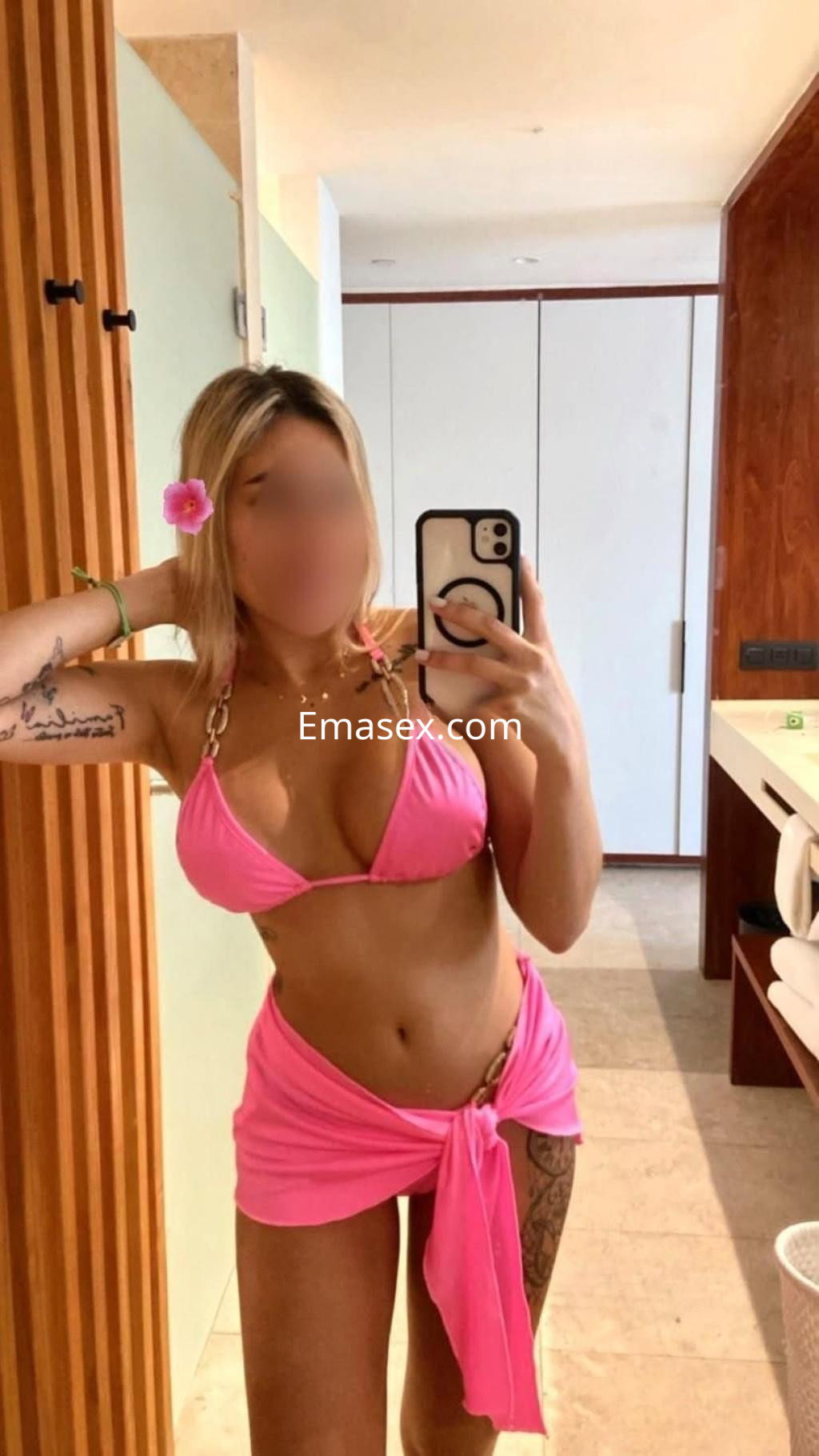 Puta con bikini rosa y pareo del mismo color, posando frente al espejo en un ambiente interior de Valencia.