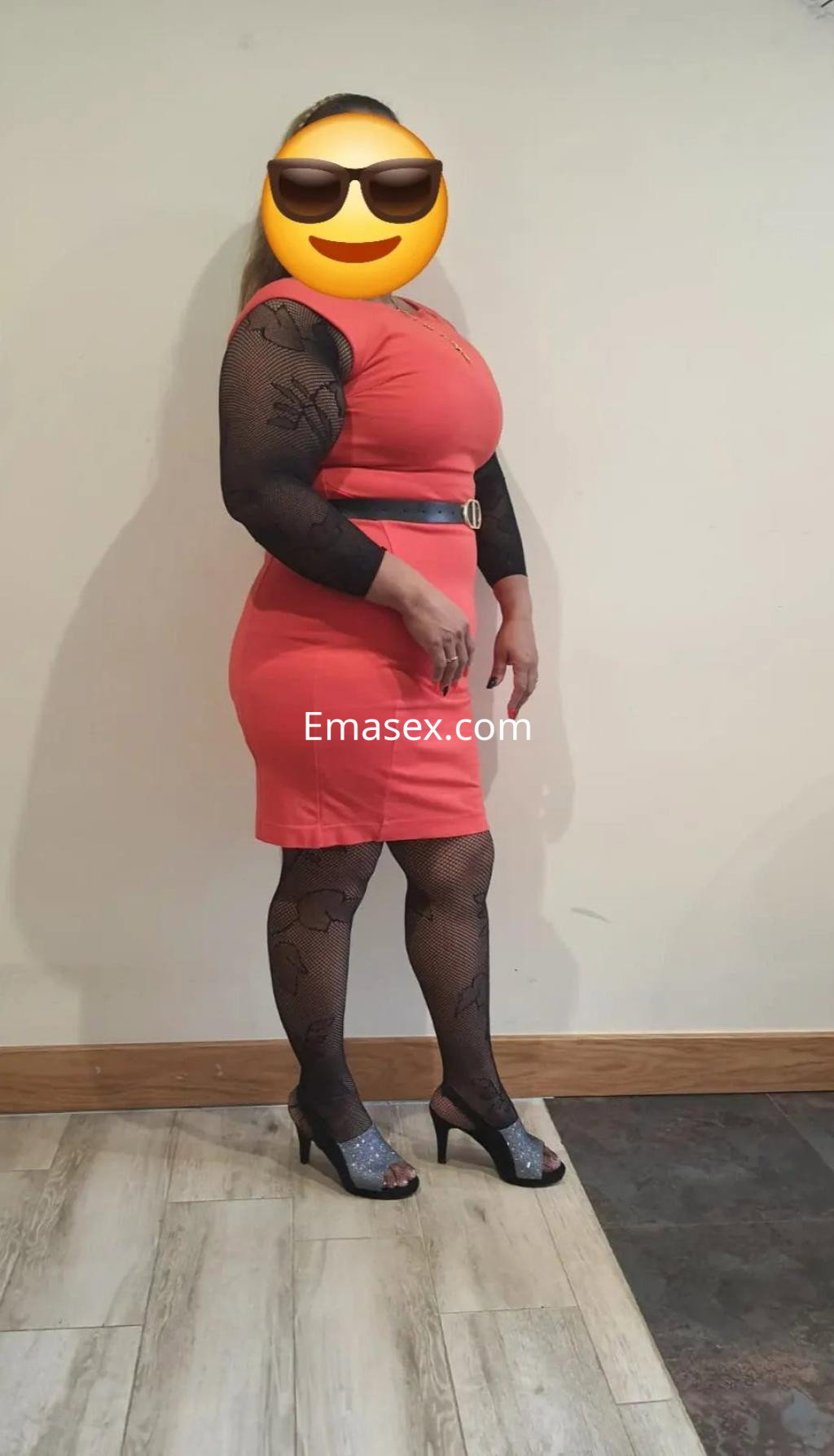 Puta posando de perfil en Santander, lleva un vestido rojo ajustado y medias negras con diseño, complementado con tacones.