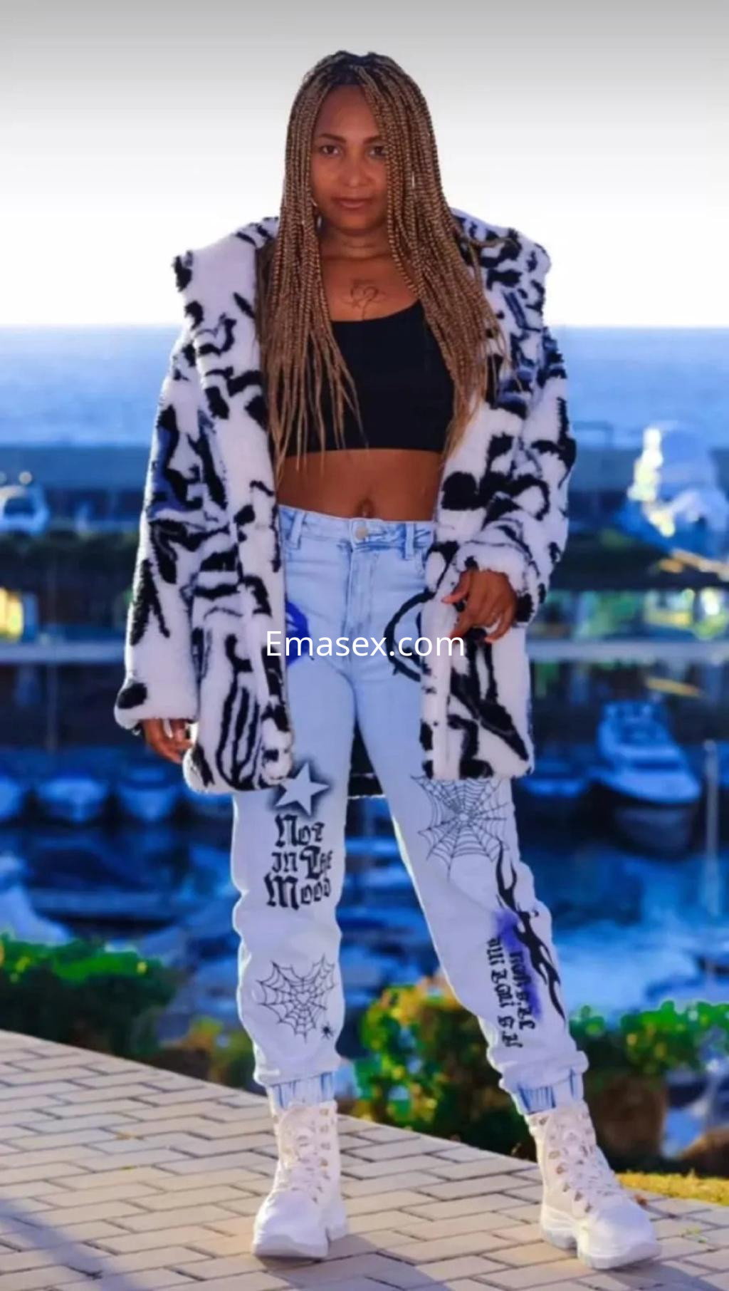 Puta con cabello trenzado, vestida con chaqueta de pelaje y pantalones claros, en un puerto de Palma de Mallorca.