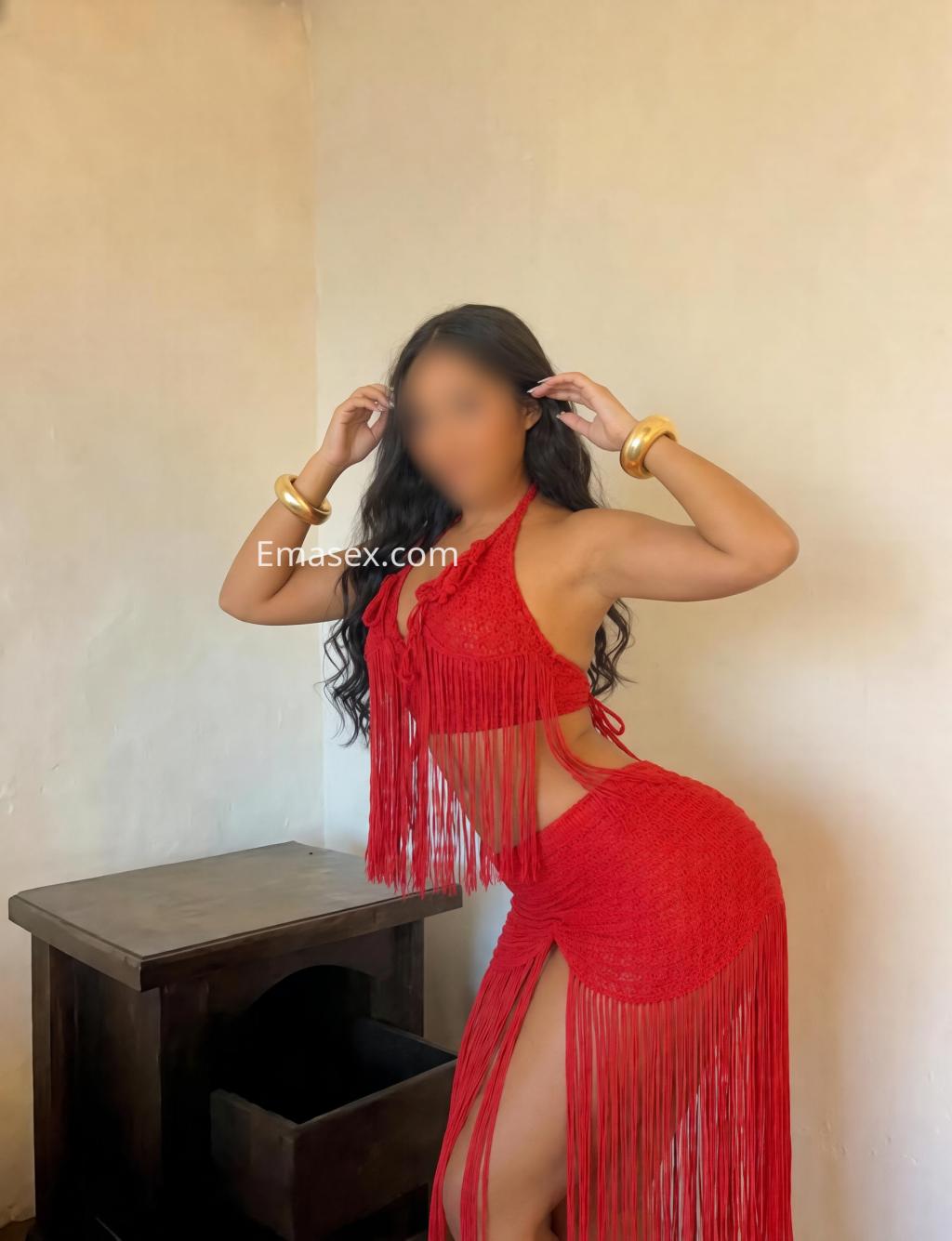 Escort en Coruña con un vestido rojo de flecos, posando de lado y mostrando una postura elegante.
